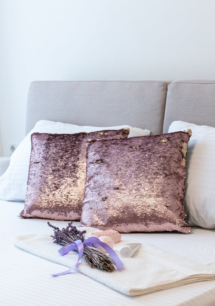 journey Cushions and bunch of lavender placed on soft bed covered with bed linens in bedroom